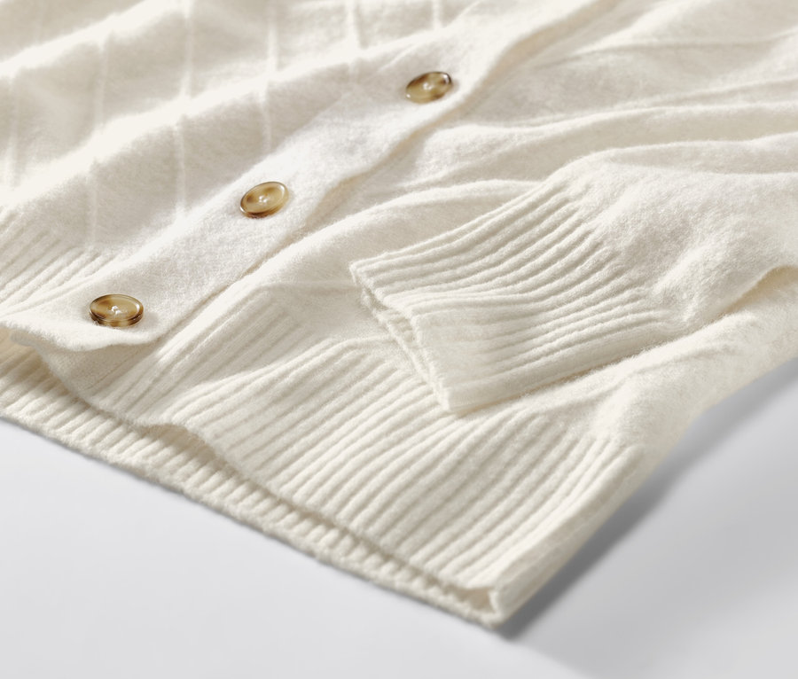 Détail d'un cardigan blanc crème avec structure tricotée.
