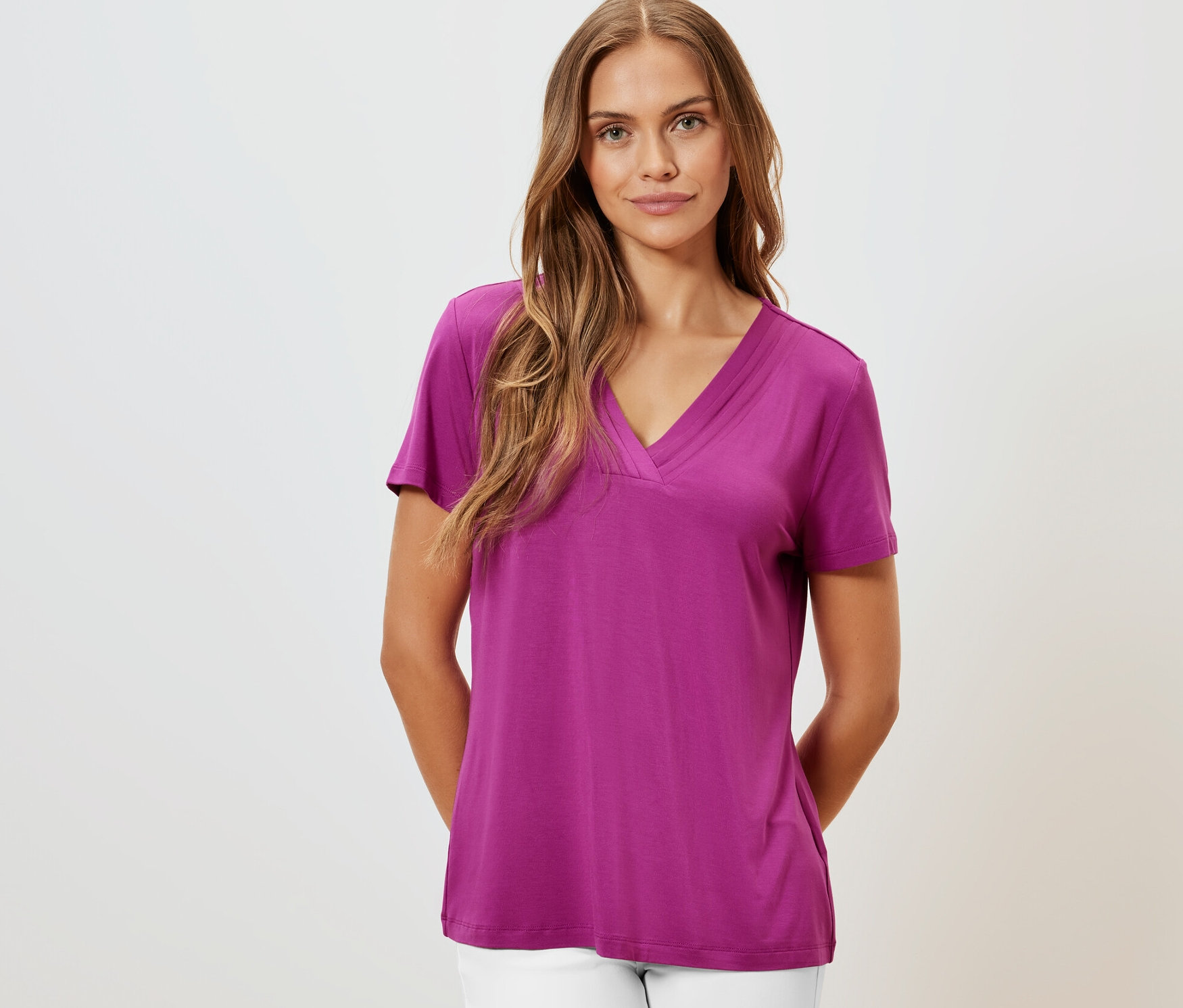 Une femme portant un t-shirt avec soufflet, baie et un pantalon blanc.