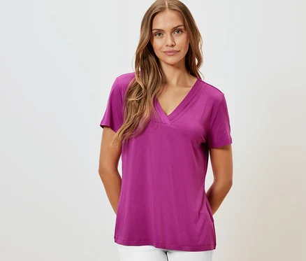 Une femme portant un t-shirt avec soufflet, baie et un pantalon blanc.