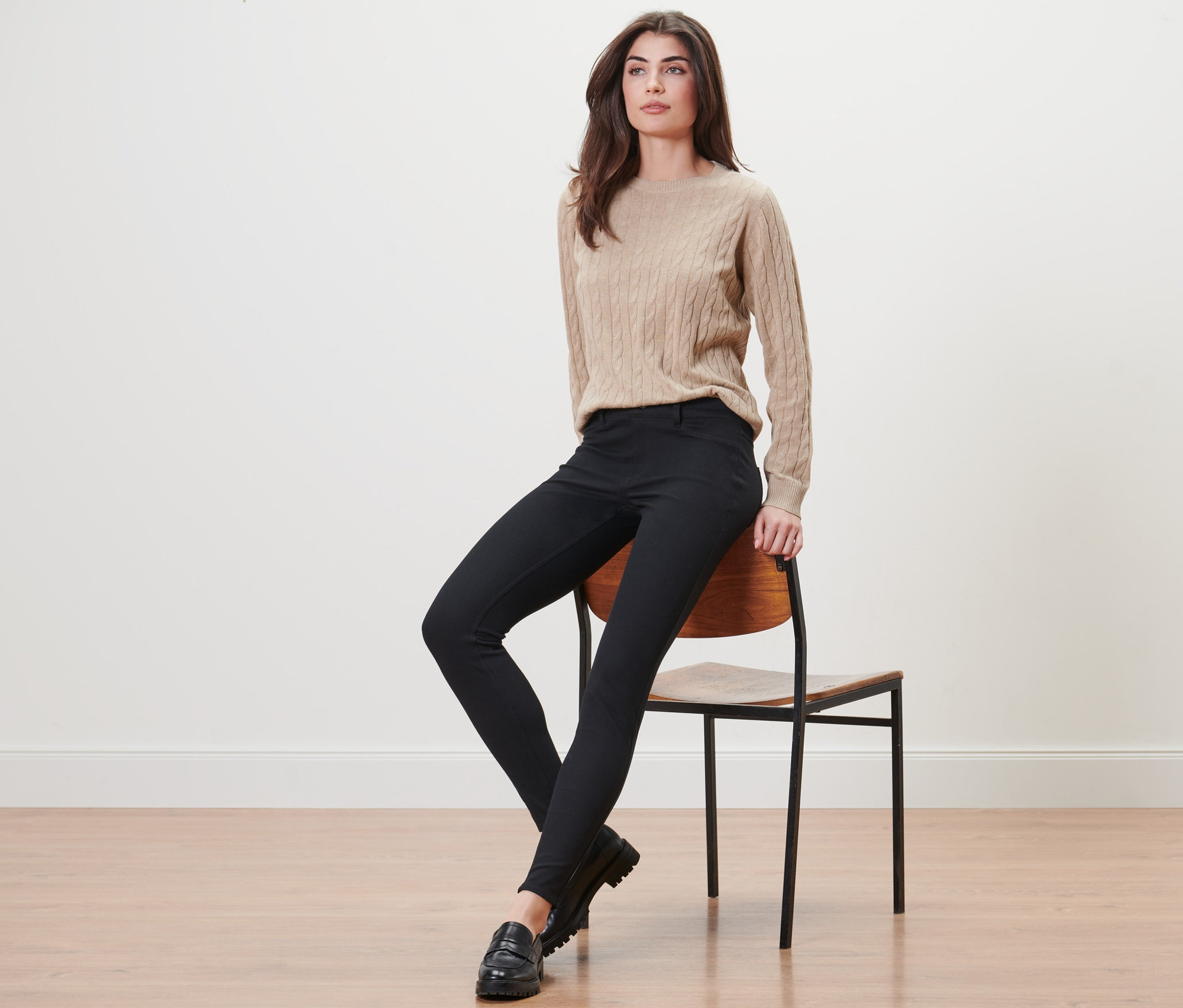Une femme est assise sur une chaise et porte un jegging noir.