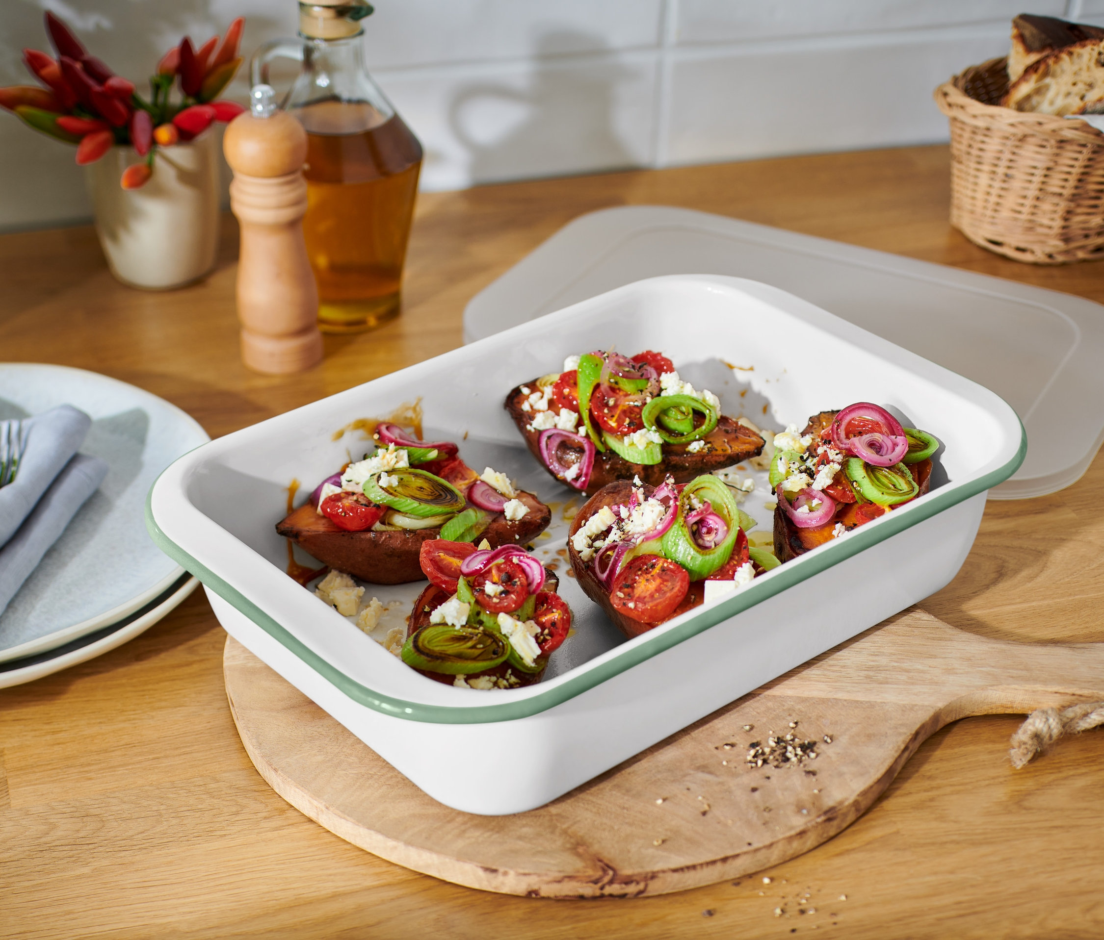 Patates douces cuites au four avec tomates, oignons et feta dans un grand moule à gratin en émail avec couvercle.