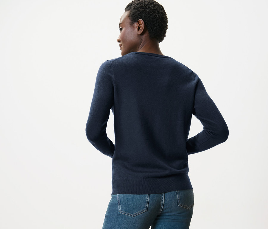 Vue arrière d'une femme portant un pull en maille fine de mérinos bleu foncé et un jean bleu.