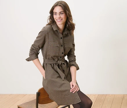Femme assise sur une chaise portant une robe en sweat à jacquard pied-de-poule.