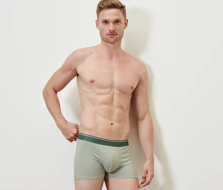 Un homme pose sur un fond blanc portant des 4 boxers.