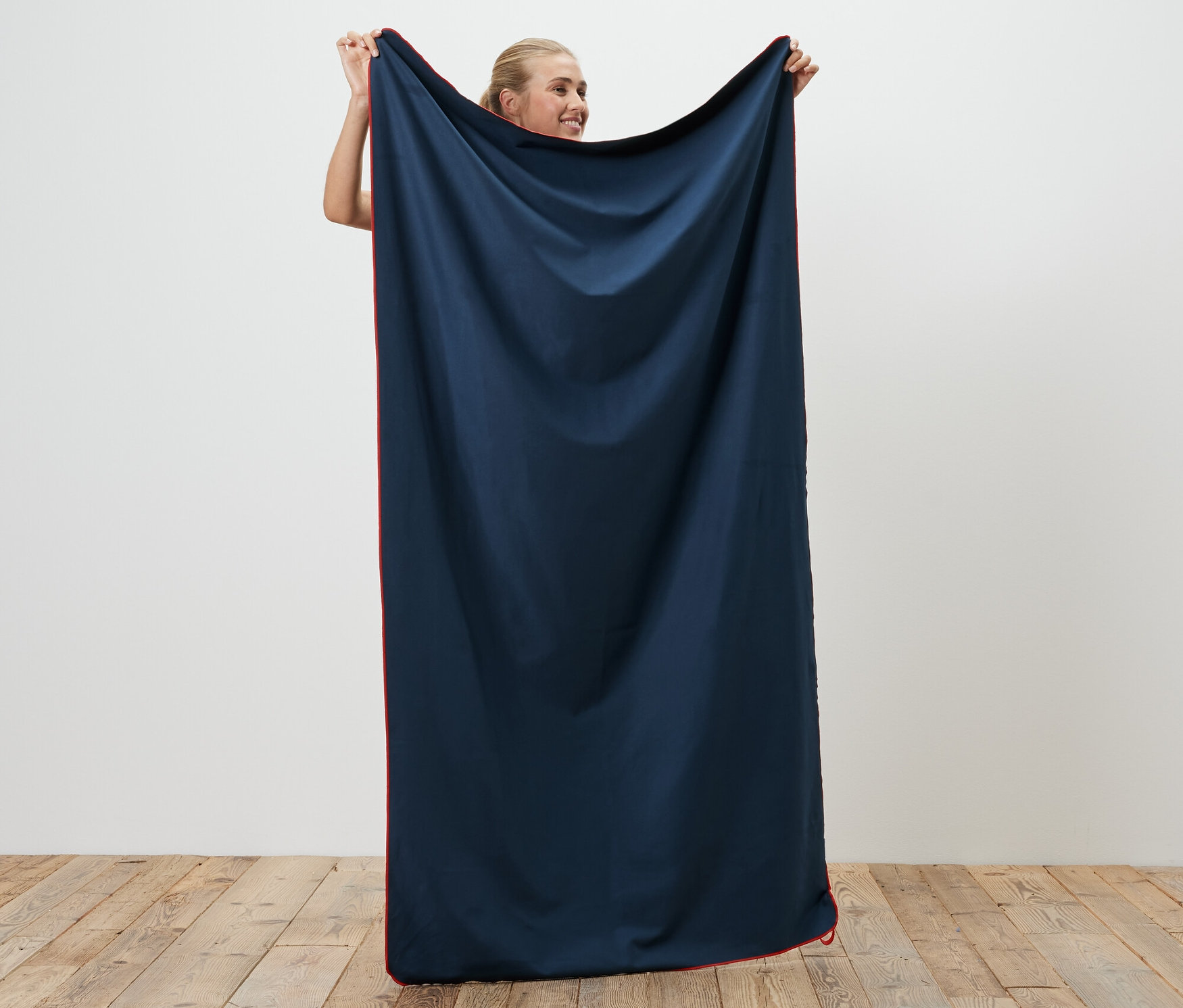 Femme tenant une serviette de toilette d’extérieur, env. 50 x 100 cm.