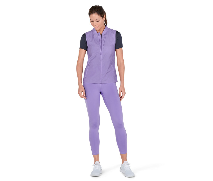Femme portant une veste de sport 3-en-1 violette, un legging et des baskets.
