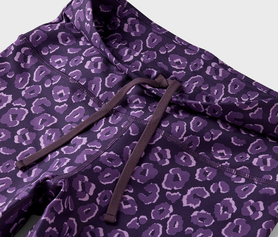 Gros plan sur un legging violet avec un motif animal et un cordon de serrage marron à la taille.