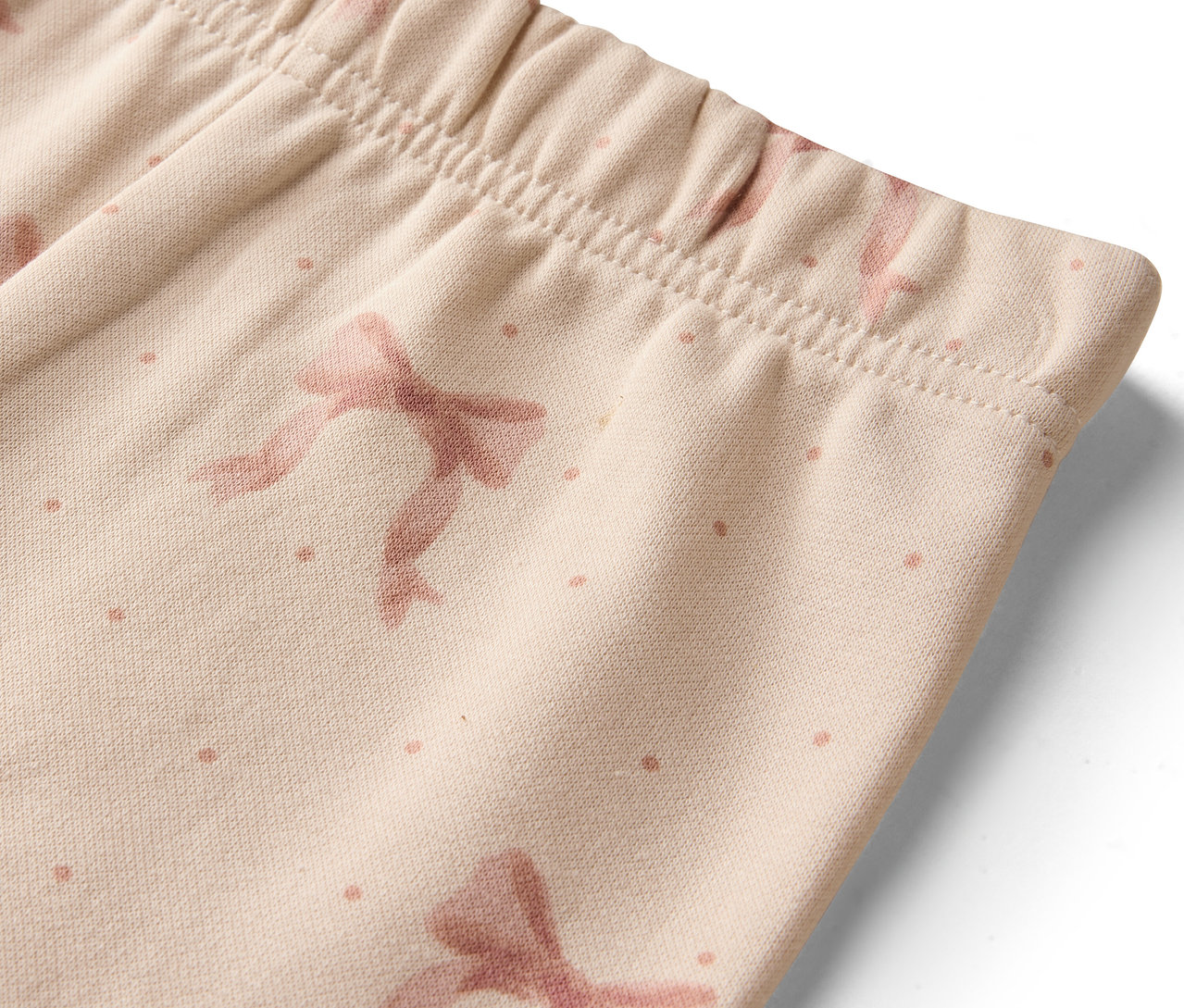 Détail de leggings beiges avec des nœuds et des points.