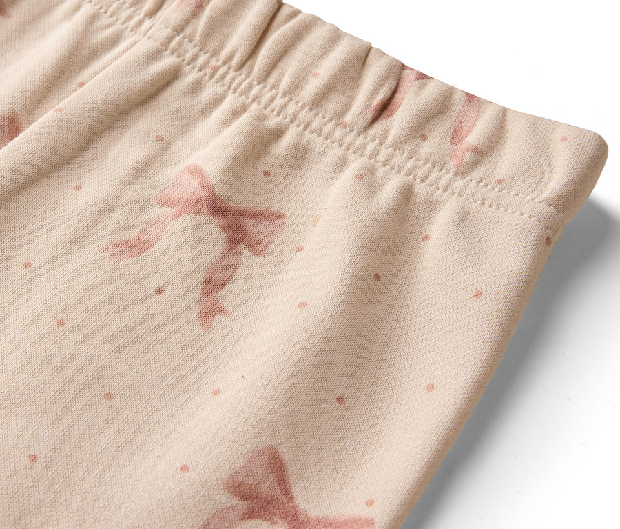 Détail de leggings beiges avec des nœuds et des points.