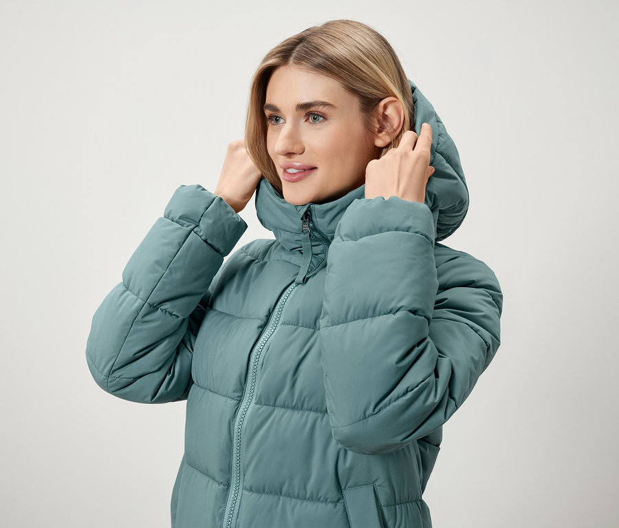 Femme ajustant la capuche d'une doudoune bleu turquoise.