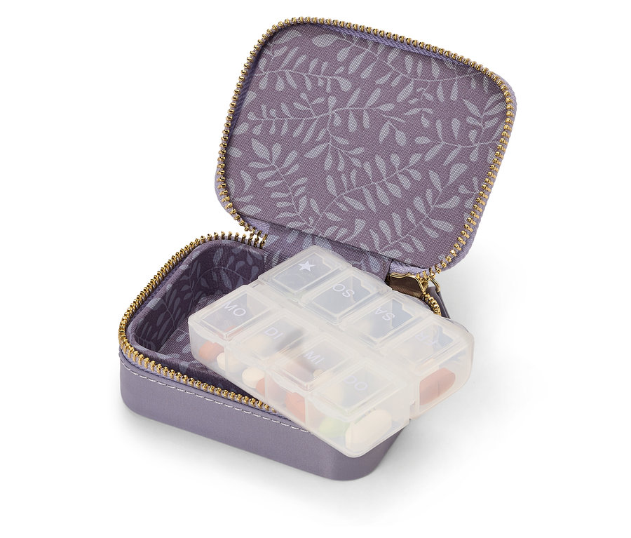 Trousse de voyage violette ouverte avec un distributeur de médicaments hebdomadaire.