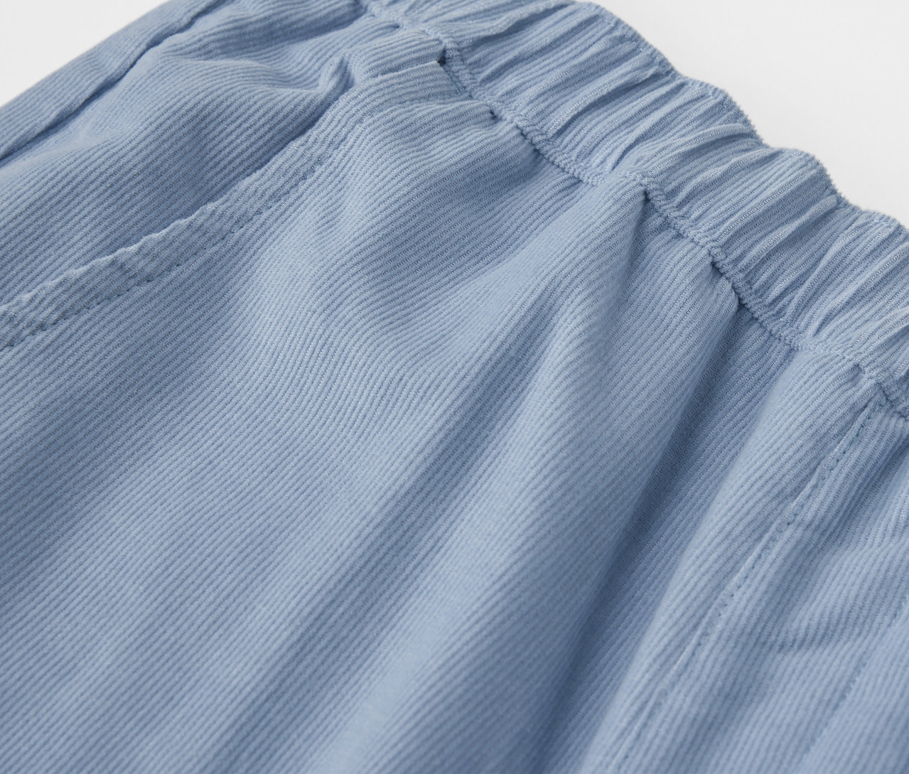 Gros plan sur un pantalon d’extérieur en velours côtelé bleu pour enfants avec une taille élastique.