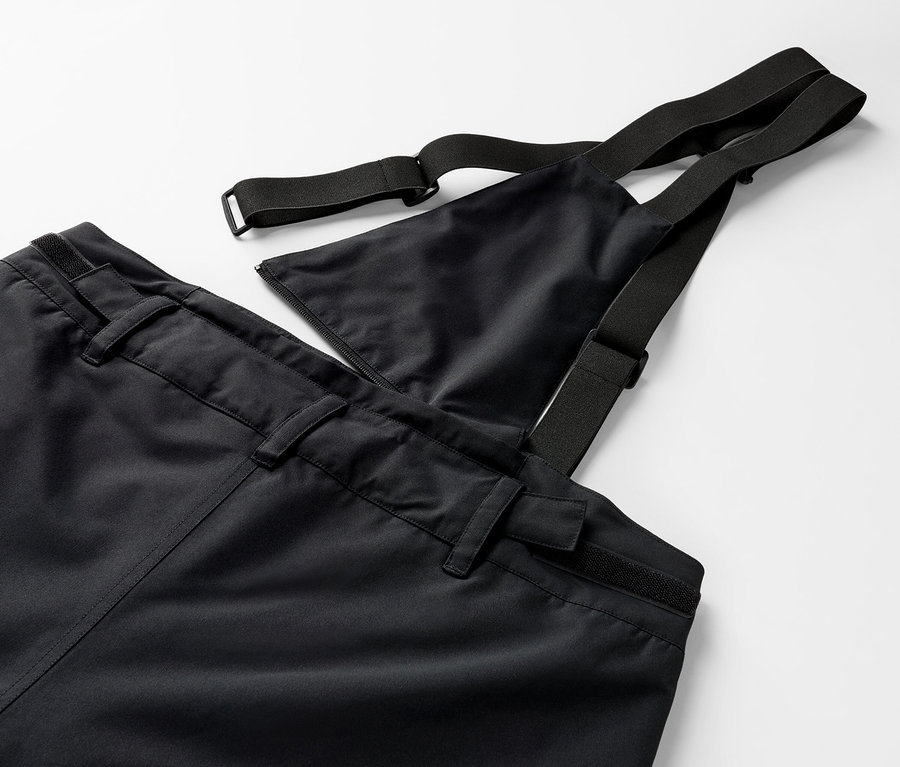 Gros plan d'un pantalon noir à bavette avec des bretelles élastiques.