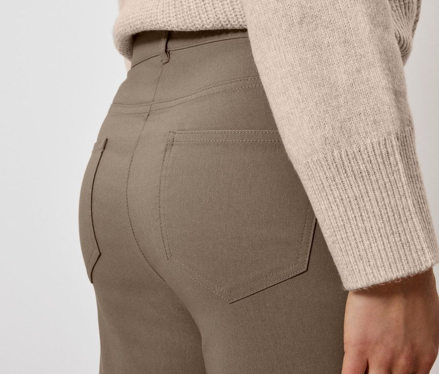Gros plan d'une femme portant un pantalon marron et un pull beige.