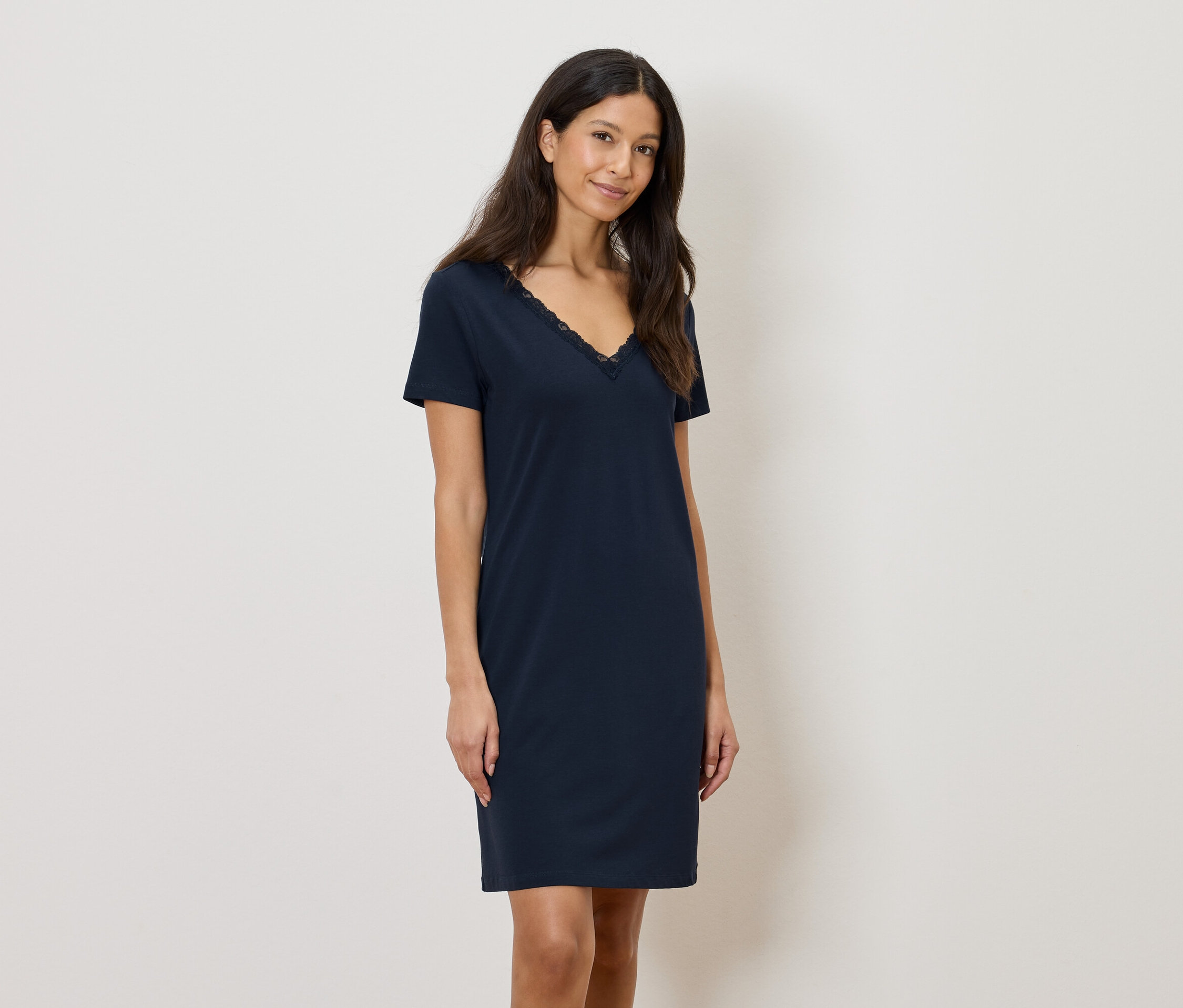 Femme portant une robe bleu marine arrivant au genou avec des finitions en dentelle à l'encolure en V.