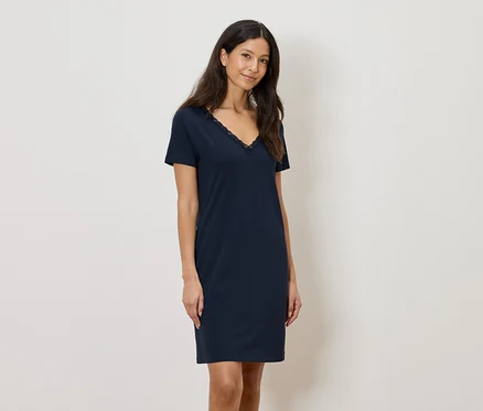 Femme portant une robe bleu marine arrivant au genou avec des finitions en dentelle à l'encolure en V.