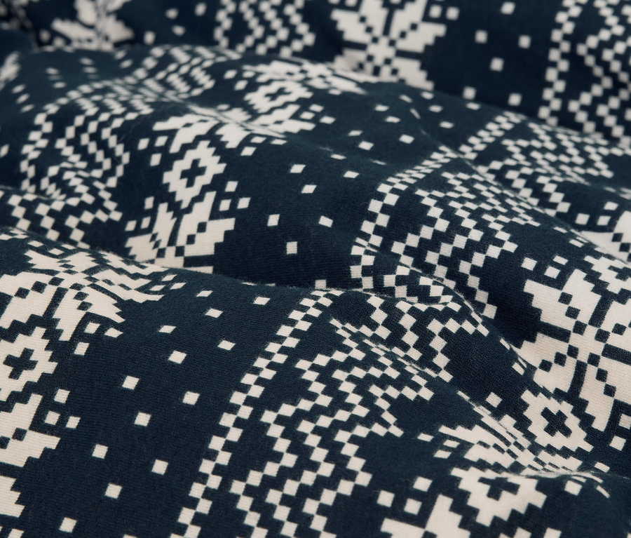 Gros plan d'un tissu avec un motif de flocons de neige pixélisé en bleu marine et blanc.