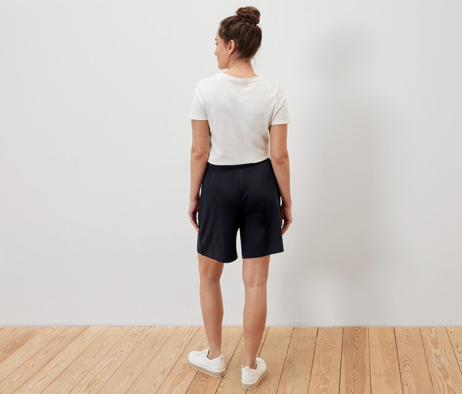 Une femme se tient dos à la caméra et porte un short en jersey noir.