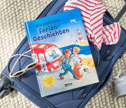 Sur une valise bleue sont posés le livre « Les plus belles histoires de vacances » (en allemand), des lunettes de soleil et un t-shirt rayé.