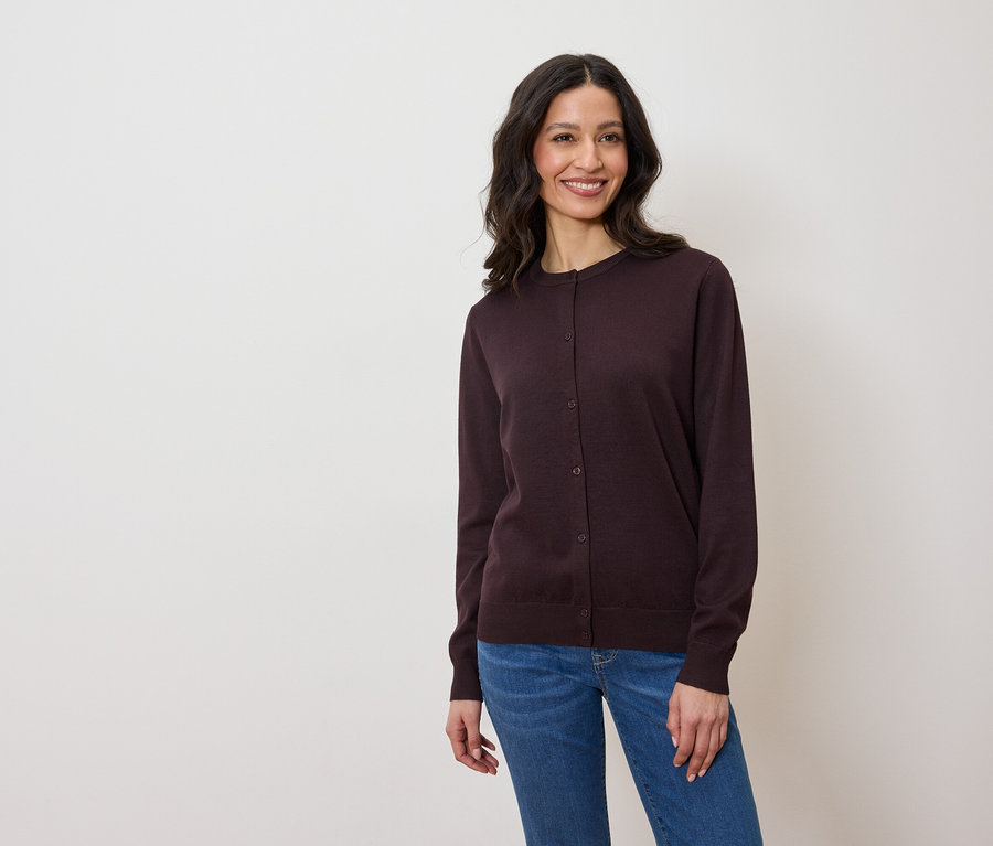 Une femme porte un cardigan violet foncé et un jean.