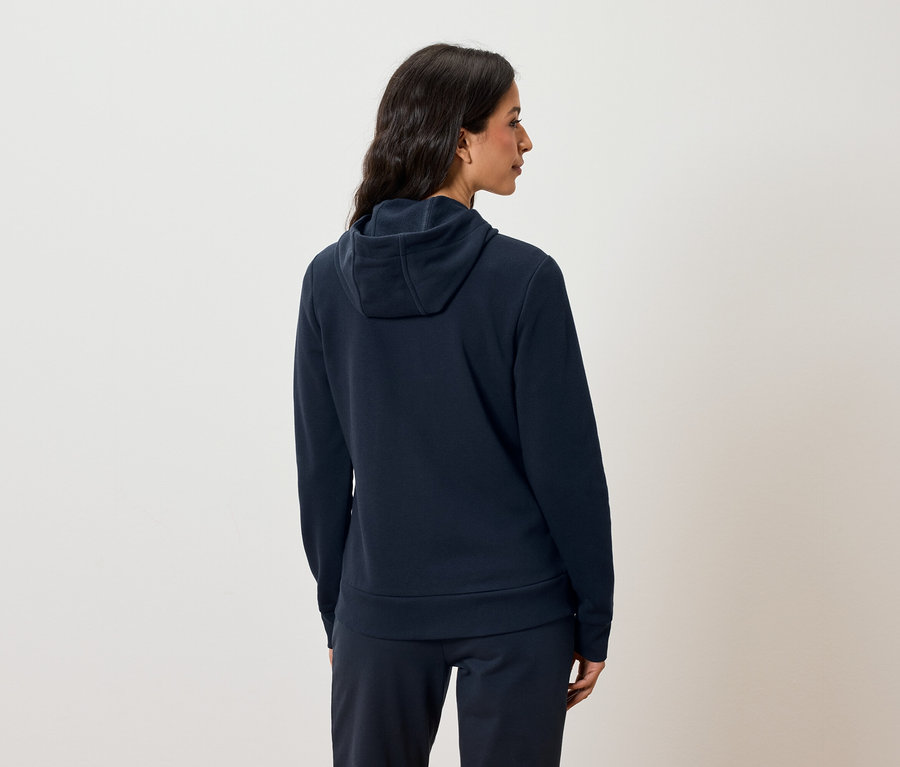 Femme vue de dos portant un sweat à capuche bleu marine et un pantalon de jogging.