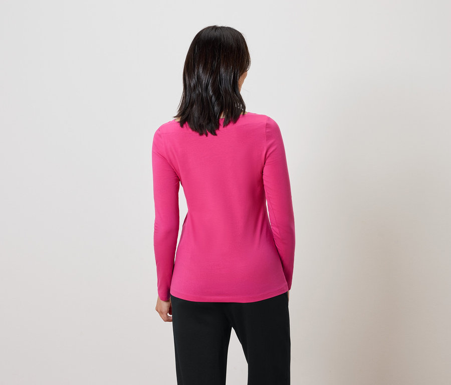 Vue arrière d'une femme aux cheveux foncés portant un pull rose et un pantalon noir.