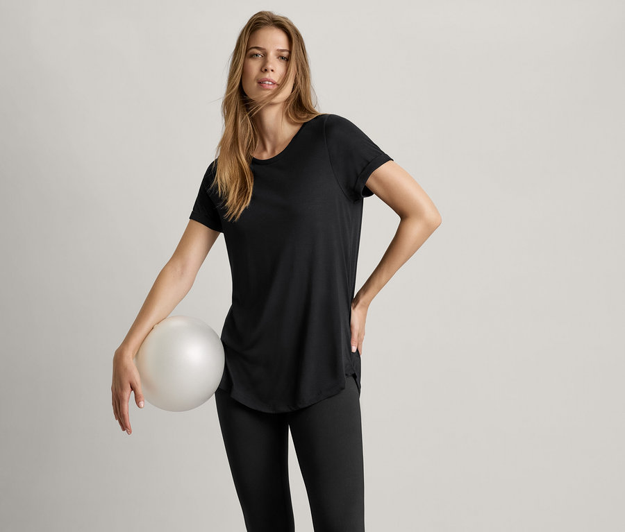 Femme tenant un ballon et portant un t-shirt long noir.