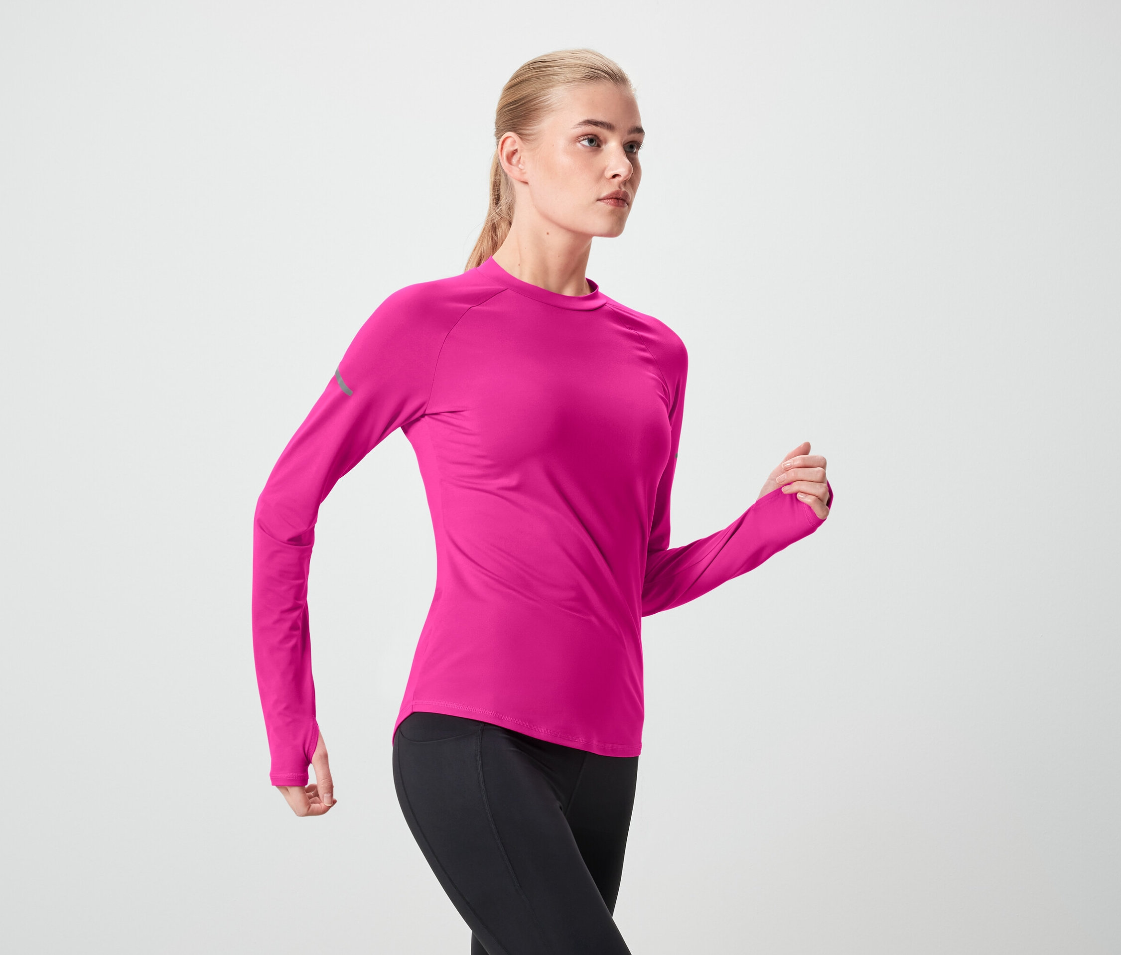 Femme en haut de sport rose et leggings noirs en mouvement.