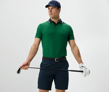 Un homme tenant un club de golf porte un polo fonctionnel vert.