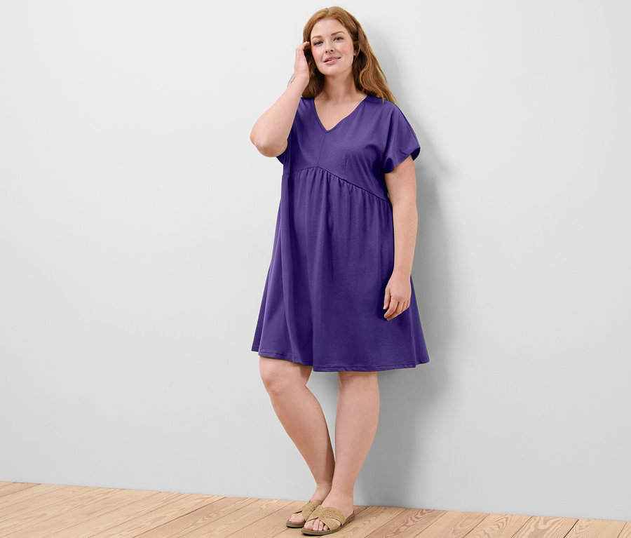 Une femme pose dans une robe en jersey violette.