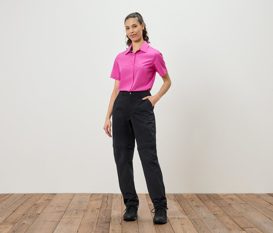Femme portant une chemise rose et un pantalon noir arrivant au genou.
