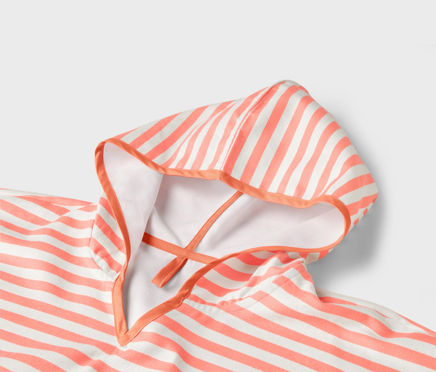 Gros plan sur un poncho de bain à capuche rayé blanc et corail.