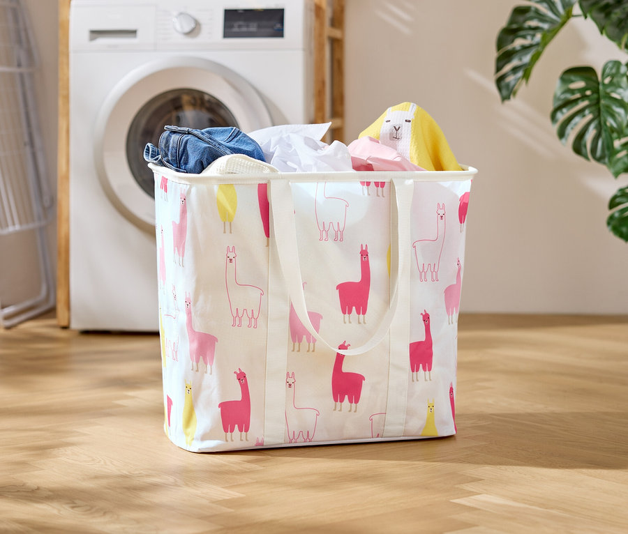 Un panier à linge à motif lama se trouve devant une machine à laver dans une buanderie.