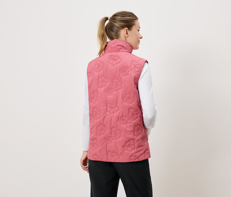 Femme vue de dos, portant un gilet matelassé rose avec un motif floral.