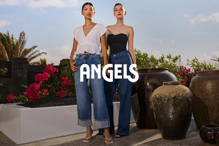 Deux femmes posent à l'extérieur, l'une portant un chemisier blanc et un jean, l'autre un haut noir sans bretelles et un jean.