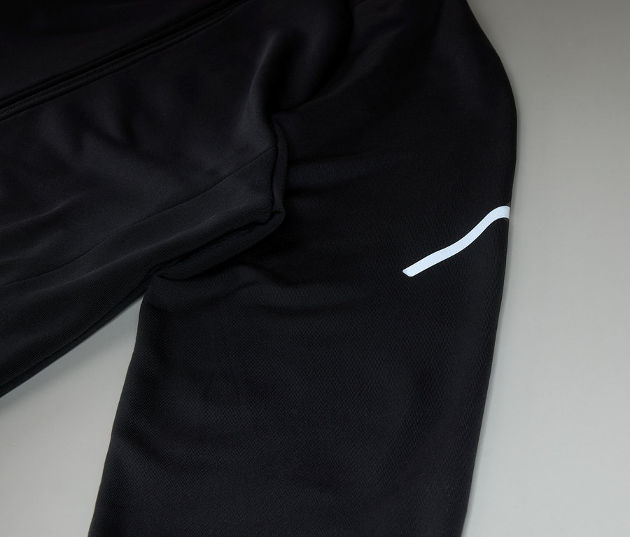 Gros plan d'un pantalon de survêtement noir avec une bande blanche sur la jambe droite.