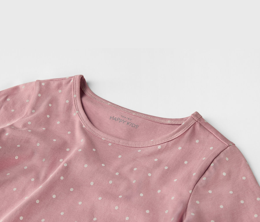 Gros plan d'un t-shirt rose à pois blancs "HAPPY KIDS".