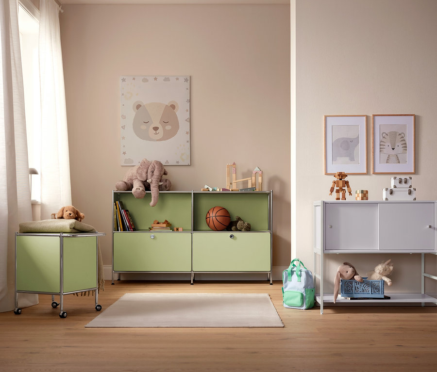 Une chambre d'enfant avec des armoires de rangement vert clair et blanches, des jouets et des photos au mur.