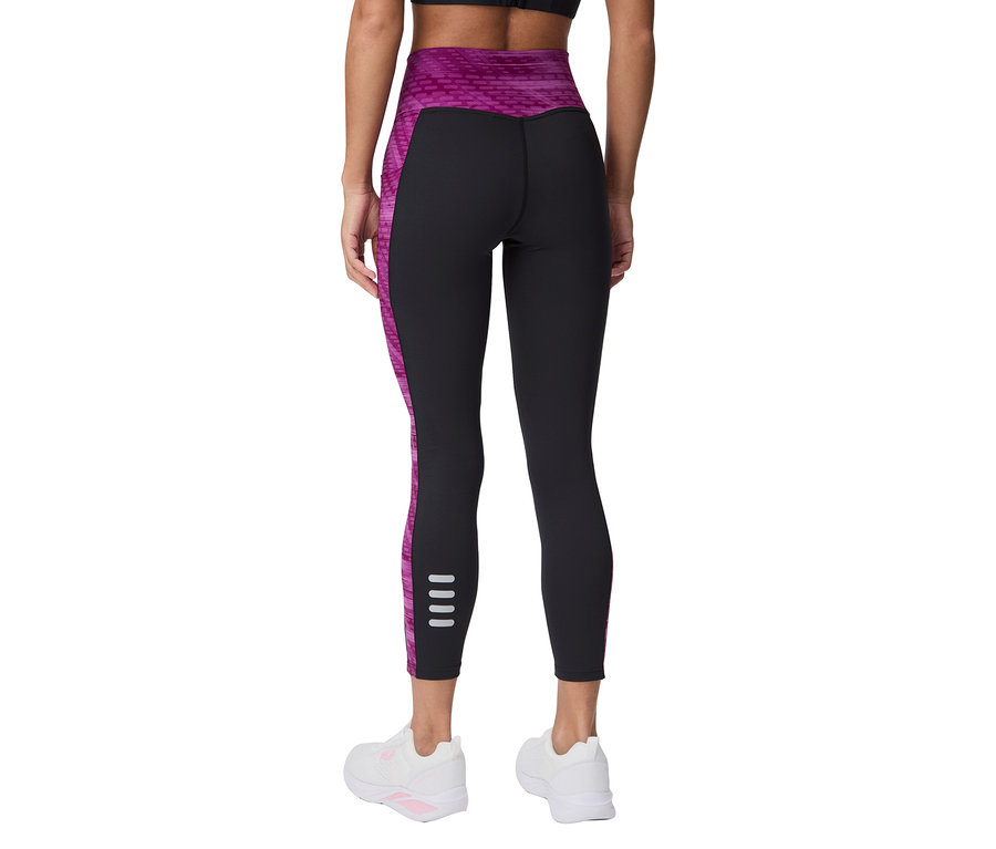 Vue arrière d'une femme portant des leggings noirs avec des accents roses et des baskets blanches.