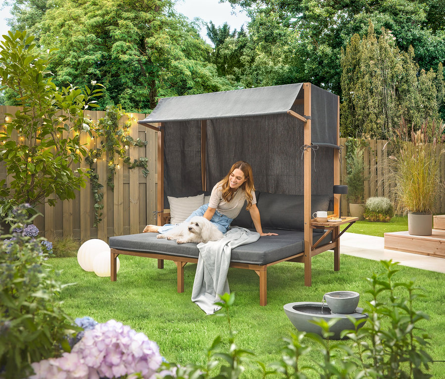 Femme assise avec un chien sur une fontaine de jardin solaire dans le jardin.