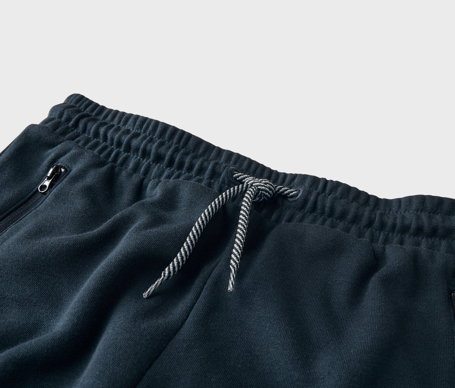 Gros plan d'un pantalon de survêtement bleu marine avec cordon de serrage et poche zippée.