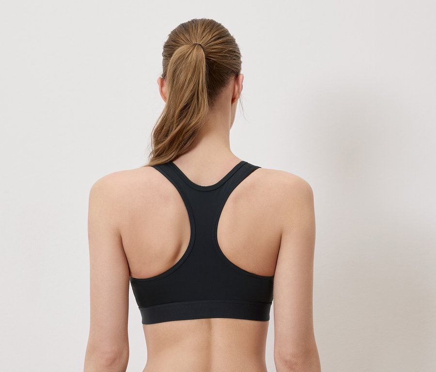 Vue arrière d'une femme portant un soutien-gorge de sport noir et une queue de cheval.