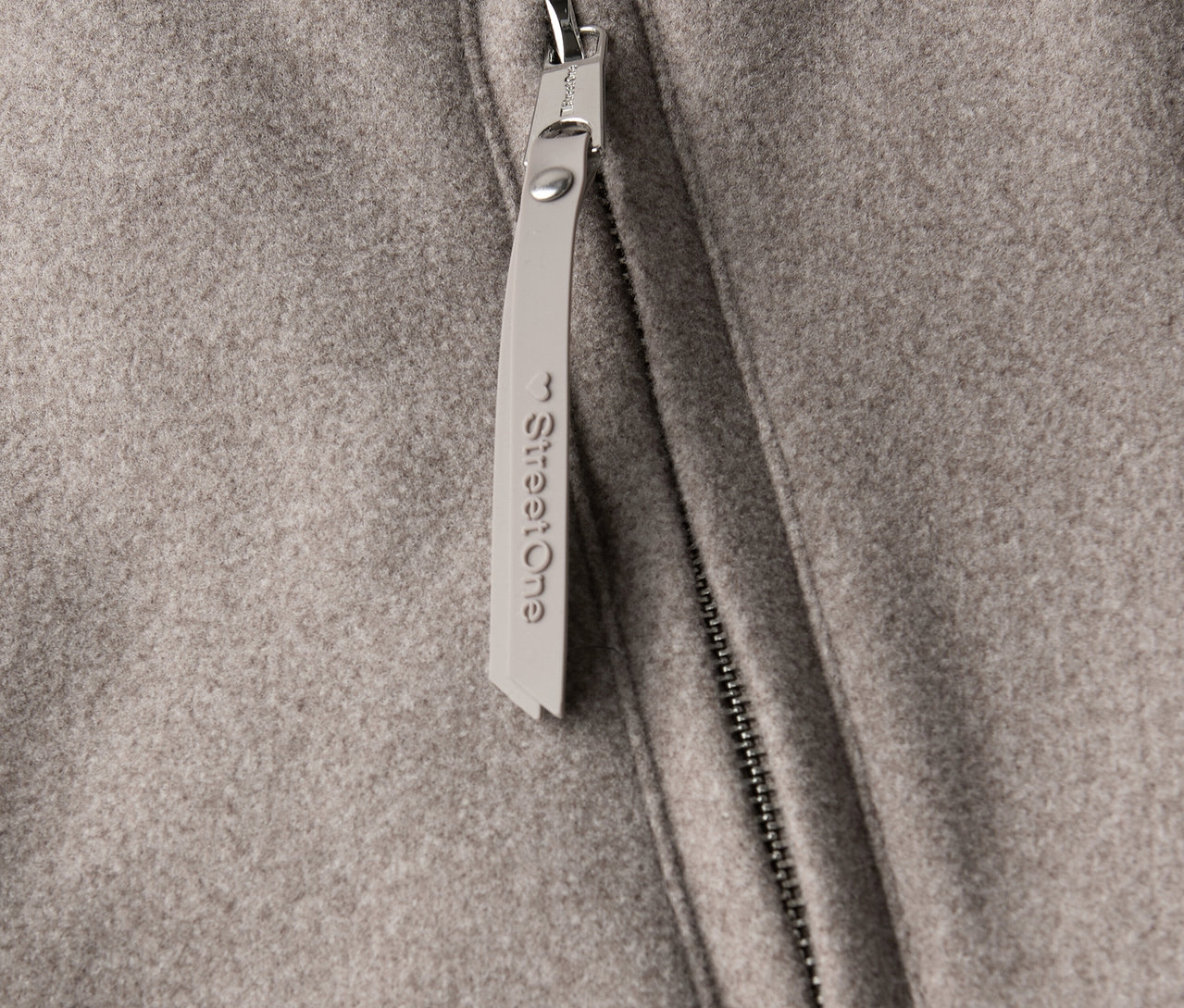 Gros plan sur un manteau court Street One avec fermeture éclair et pendentif.