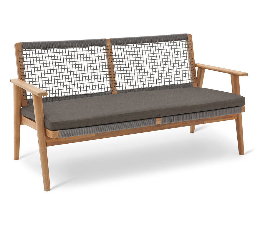 Un banc de jardin en bois avec un coussin d'assise gris et un dossier tressé se dresse devant un fond blanc.