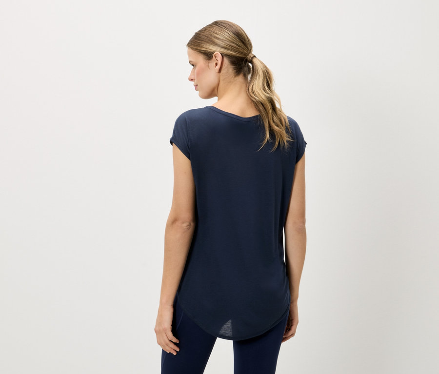 Femme vue de dos, portant un t-shirt bleu marine et un legging bleu marine sur un fond neutre.