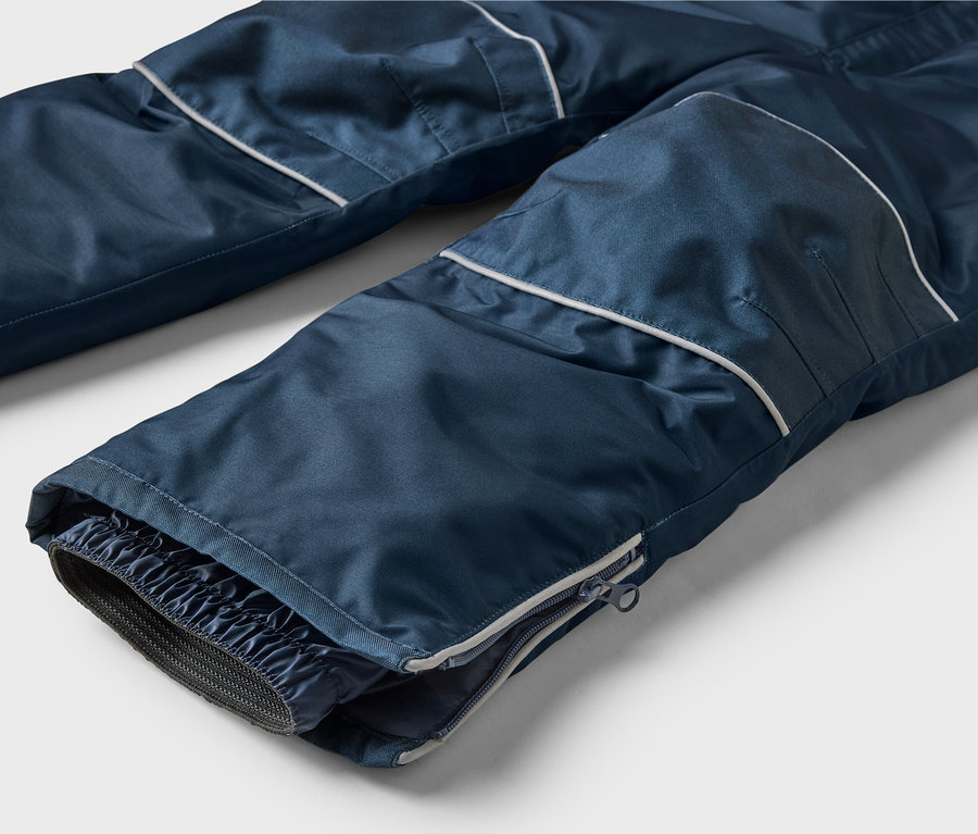 Gros plan d'un pantalon bleu marine avec une bande blanche et une fermeture éclair en bas de la jambe.