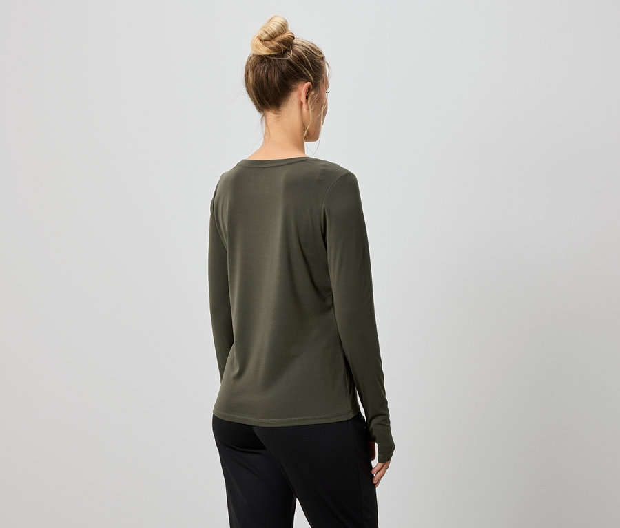 Vue arrière d'une femme avec un chignon portant un T-shirt à manches longues olive et un pantalon noir.