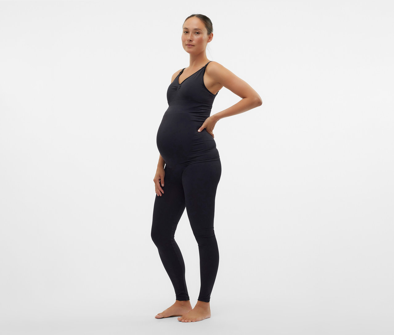 Femme enceinte portant un haut noir et un Skinny Leggings MAMALICIOUS «
MLTIA JEANNE
» posant de profil.