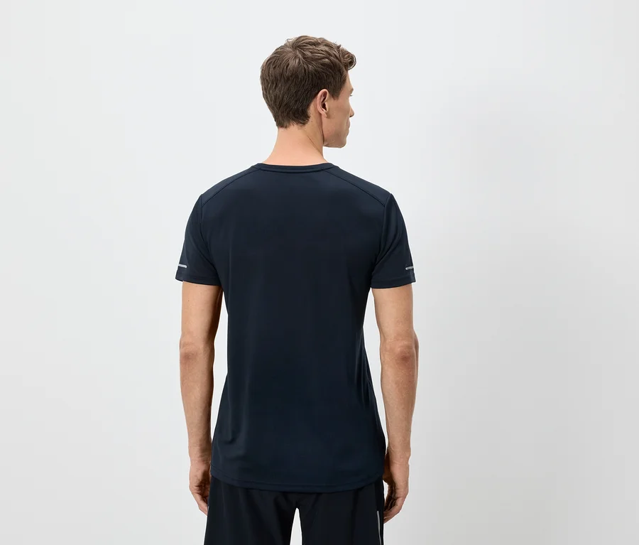 Un homme vu de dos porte un t-shirt bleu marine et un short noir sur fond blanc.