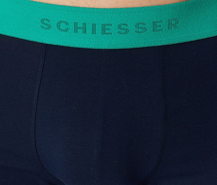 Gros plan d'un sous-vêtement bleu marine avec une ceinture vert vif, sur laquelle est inscrit 'SCHIESSER' en lettres vert foncé.